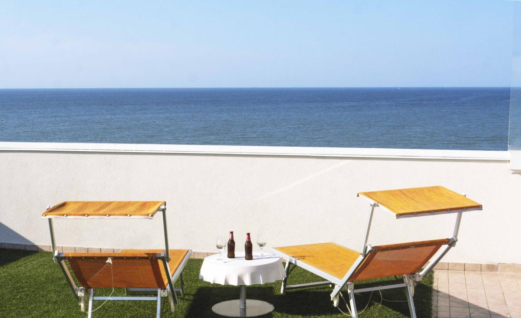 Two sun loungers with sea view, sunshine, and drinks on a table.