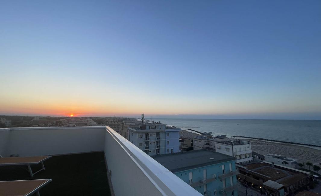 Sunset over coastal city, sea and rooftops view.