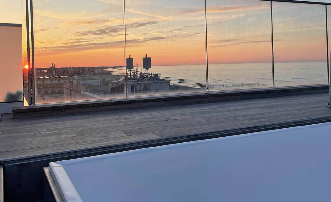 Coucher de soleil sur terrasse avec vue mer et piscine vide.