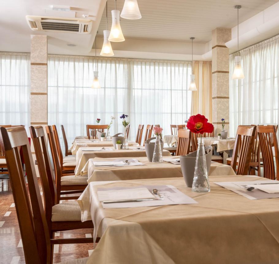 Elegant restaurant, set tables with flowers, soft lighting, welcoming atmosphere.