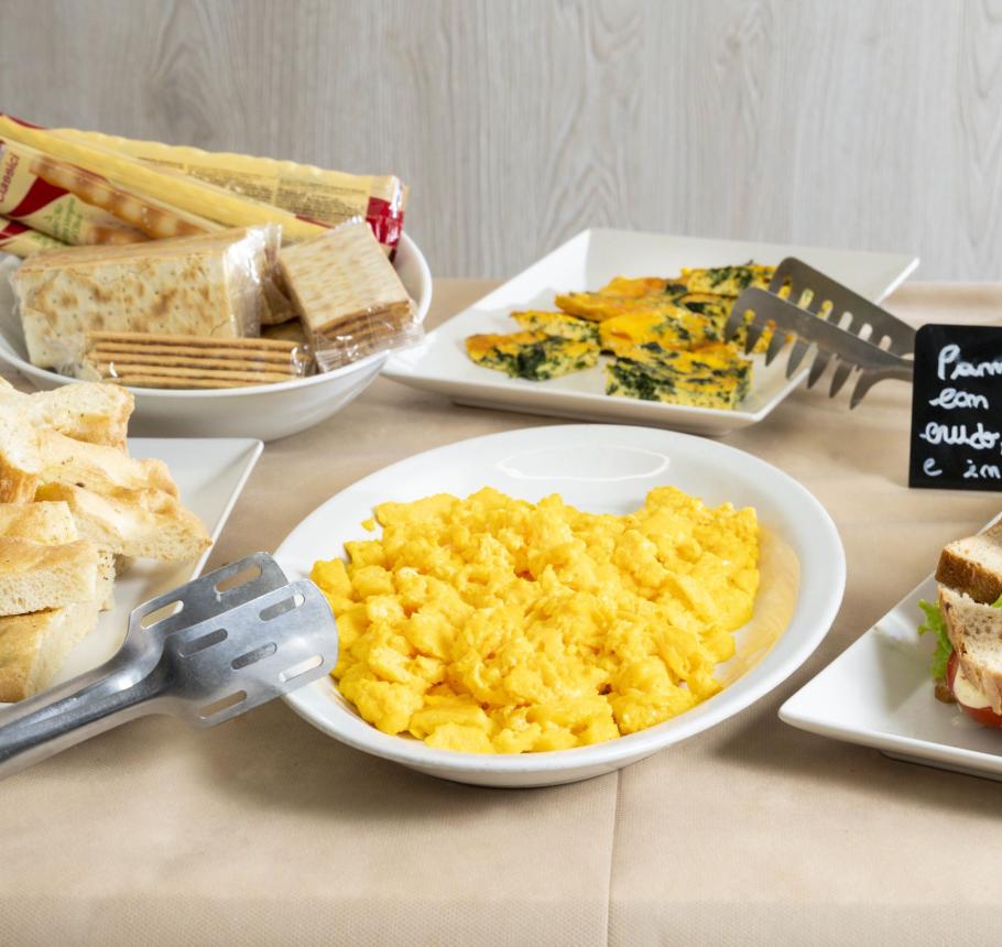 Colorful buffet with scrambled eggs, sandwiches, and delicious pastries.